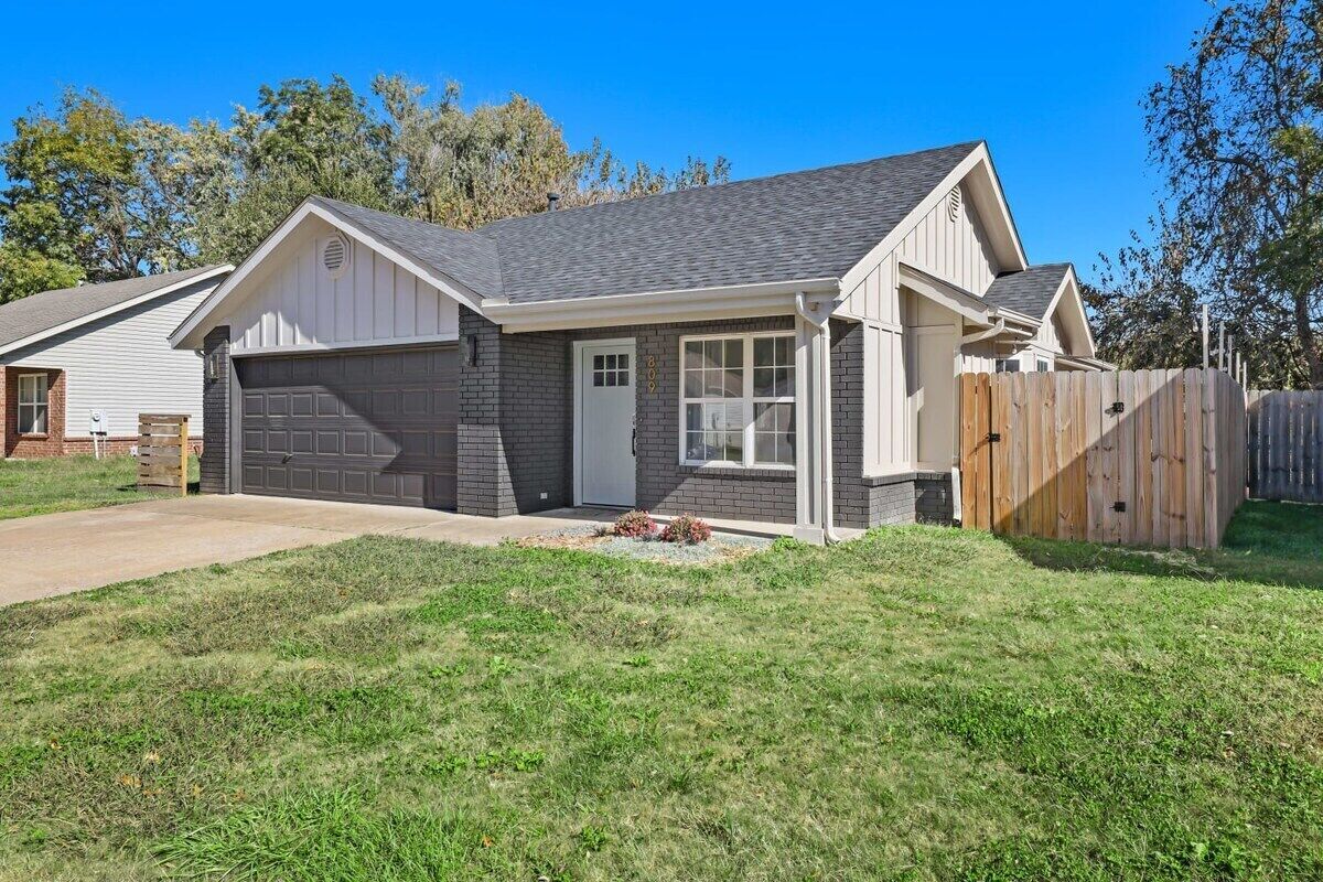 A single-story house with a garage, a covered porch, and a fenced backyard.