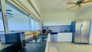 Une cuisine moderne équipée d’un lave-vaisselle, d’un réfrigérateur et d’un ventilateur de plafond.