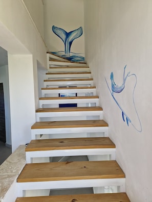 A staircase with wooden steps and a wall mural of a whale tail.