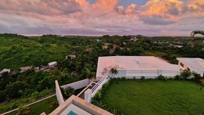 Un quartier résidentiel avec un grand bâtiment blanc, une végétation luxuriante et un ciel nuageux.