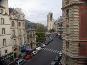 A street view with buildings, a church tower, and parked cars. - Central Parisian apartment. A 5 minute walk to the Notre-Dame and the Seine (Paris)
