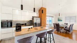 A modern kitchen with a central island, a brick chimney, and a dining area with a view.
