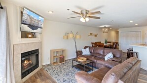 Ein Wohnzimmer mit Kamin, Ledersofa und Deckenventilator.