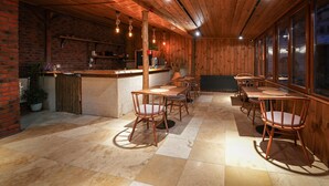 A cozy restaurant with wooden walls and a tiled floor, featuring a bar area and several dining tables with chairs. - Matiana View Cave Hotel (Nevsehir)