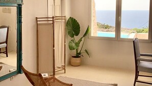 Ein geräumiges Zimmer mit Meerblick, einer großen Topfpflanze und einer Holzboden.