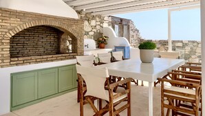 Eine rustikale Außenküche mit Backofen, Steinmauern und Blick aufs Meer.