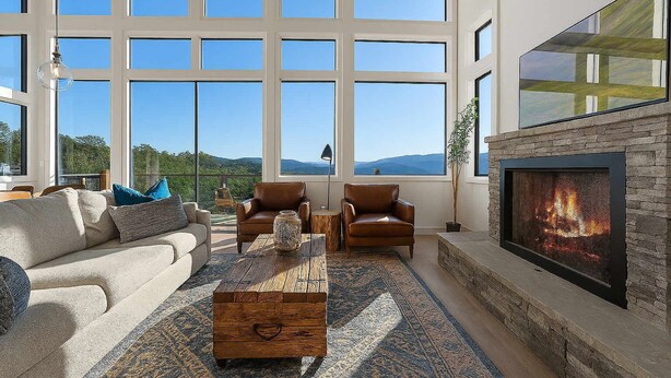 A spacious living room with large windows, a fireplace, leather chairs, and a coffee table. - Infinity View Lodge - Indoor pool & mountain views (Sevierville)