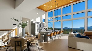 A spacious kitchen with a large island, a dining area with a round table and chairs, and a living area with a sofa and a view of the mountains. - Infinity View Lodge - Indoor pool & mountain views (Sevierville)