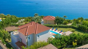 Ein Küstenanwesen mit Pool, ein Haus mit roten Ziegeln und Meerblick.