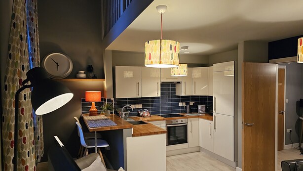 A modern kitchen with a wooden countertop, a built-in oven, and a black and white tiled backsplash. - Charming 1-bed Apartment in Newark (Newark)