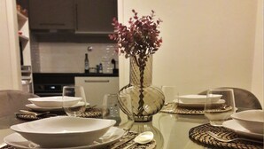 A dining table set with plates, glasses, and a vase with flowers. - Apartamento Acolhedor em Faro, a Poucos Minutos do Centro e do Barco (Faro)