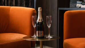 A bottle of Lanson champagne on a small round table with two glasses, flanked by two orange chairs. - Sweeney Aviemore One (Aviemore)