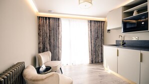A modern kitchen with a built-in microwave, a sink, and a countertop. There is a chair with a tray table and a radiator on the left. - Sweeney Aviemore One (Aviemore)