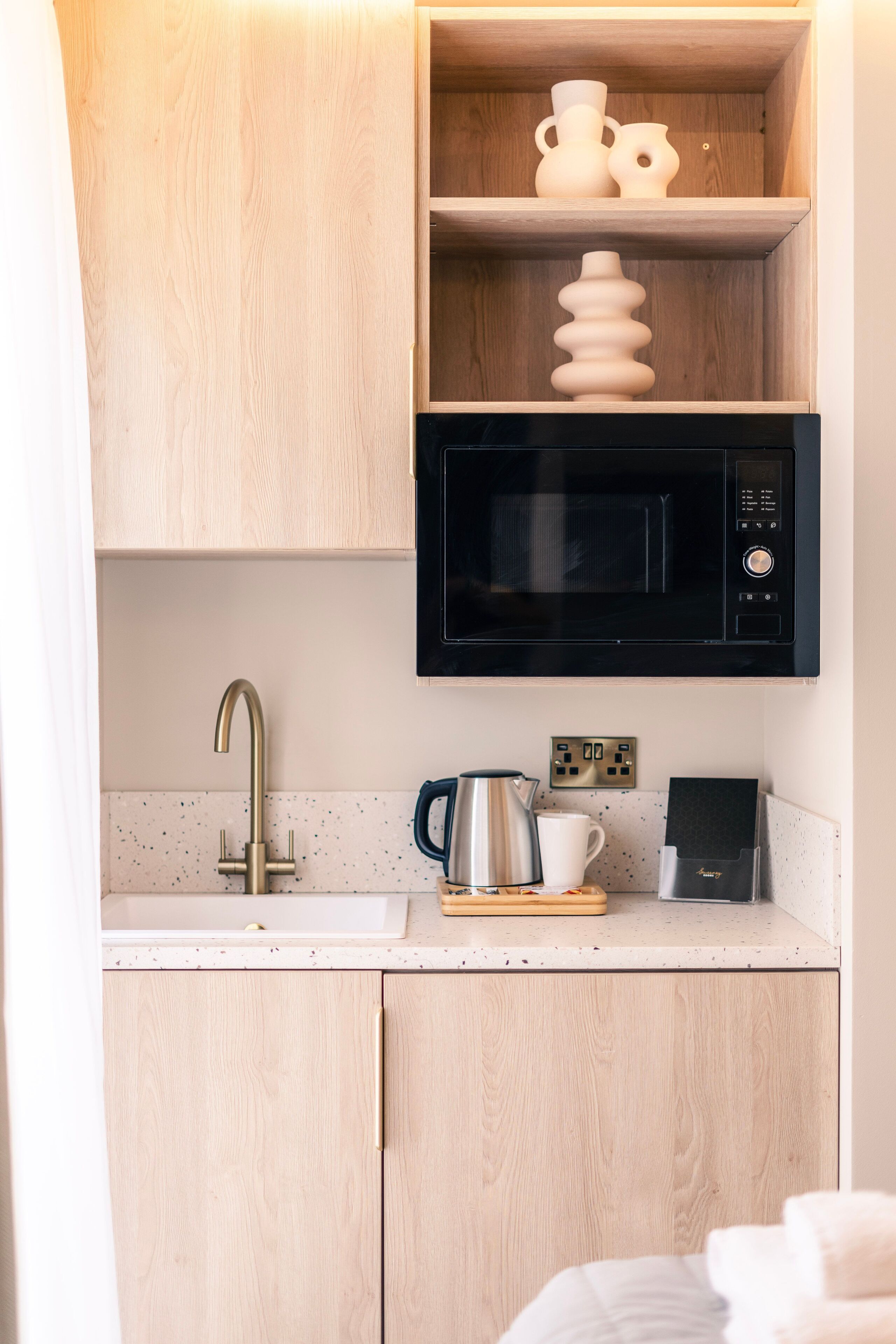 A kitchenette with a microwave, a kettle, and a coffee maker on the counter.