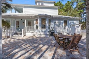 Une maison à deux étages dotée d’un patio couvert, d’une table à manger et de chaises.