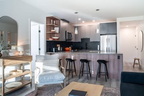 Une cuisine moderne dotée d’un îlot central, de tabourets de bar et d’un coin salon avec un canapé et des fauteuils.