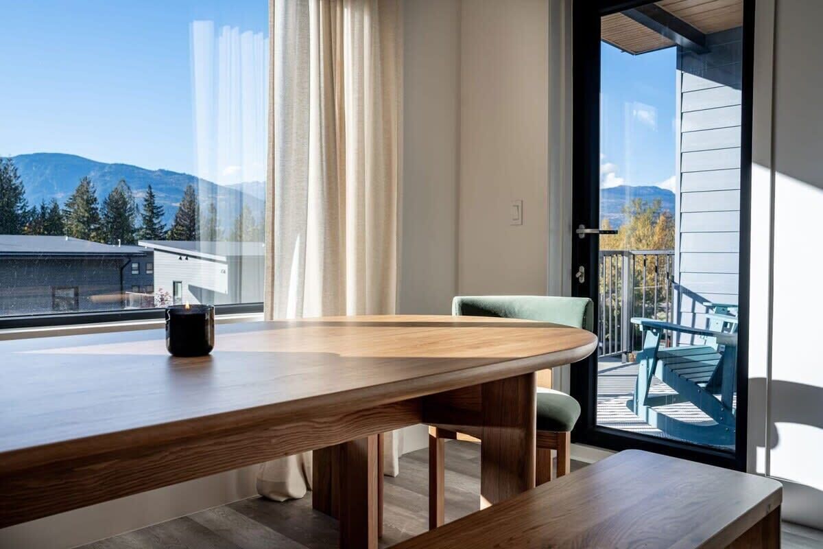 Un comedor moderno con una mesa de madera, una silla y vistas a las montañas a través de un gran ventanal.