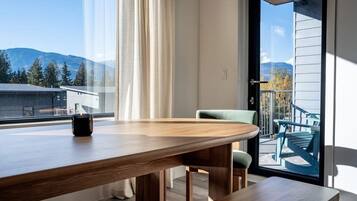 Un comedor moderno con una mesa de madera, una silla y vistas a las montañas a través de un gran ventanal.