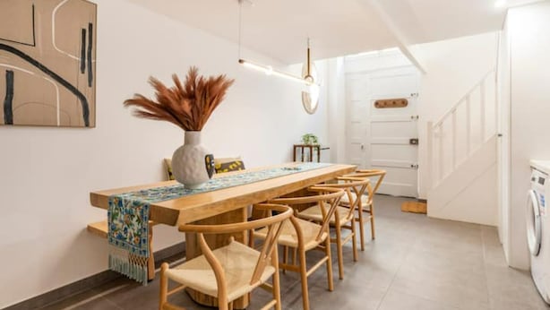 A modern dining area with a long wooden table, six wooden chairs, and a vase with dried plants. - Bellecour Pavillon (Lyon)