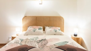 A bedroom with a woven headboard, floral bedding, and bedside lamps. - Bellecour Pavillon (Lyon)
