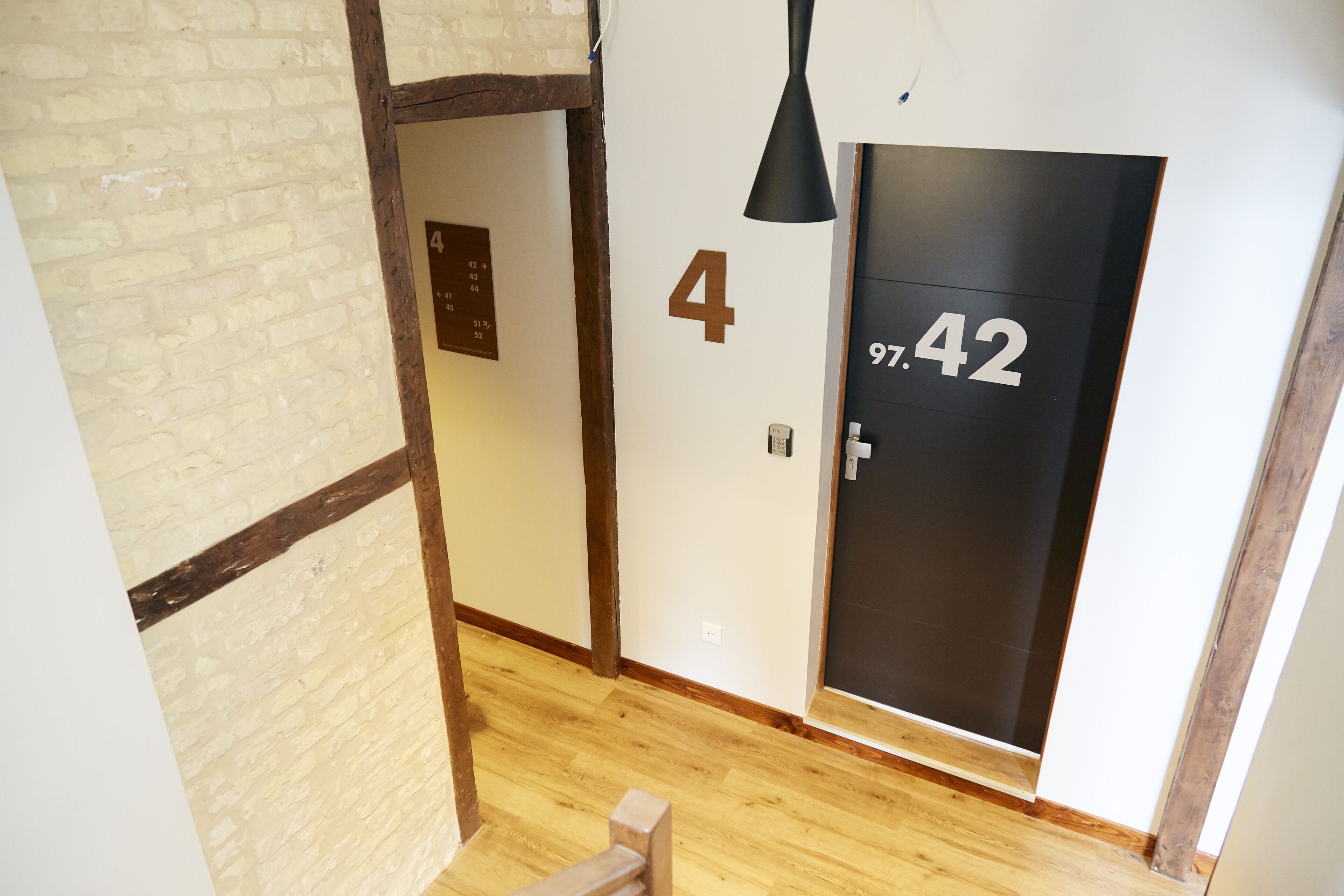 Un pasillo con suelo de madera, una puerta con la etiqueta '4' y una puerta negra con el número '97.42'.