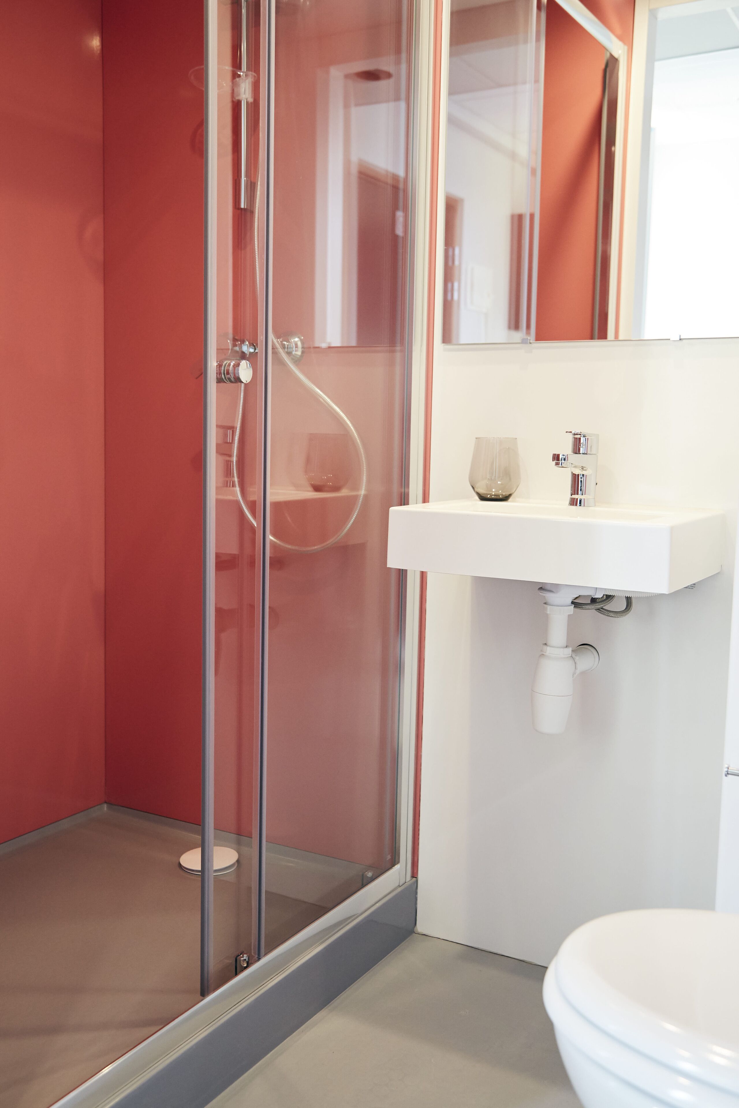 A modern bathroom with a glass shower enclosure, a white sink, and a toilet.