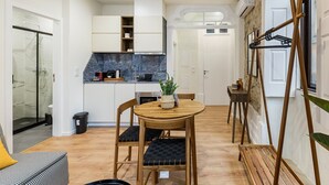 Eine kompakte Küche mit weißen Schränken, einer Marmor-Spritzschutzleiste und einem Essbereich mit Holztisch und -stühlen.