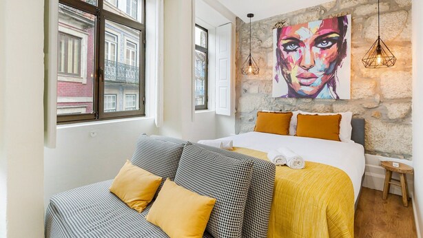 Ein Hotelzimmer mit einem Bett, einer Couch, einem großen Gemälde an der Wand und einer Steinwand.
