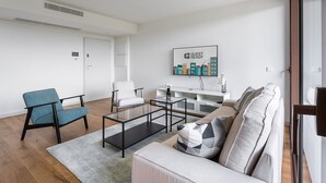 Una sala de estar moderna con un sofá, sillones, una mesa de centro y un televisor.