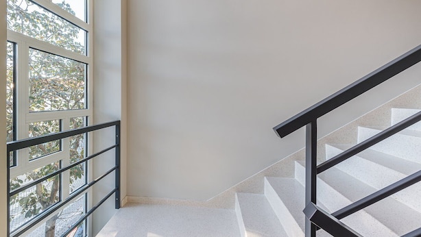 A staircase with a handrail, a white wall, and a window with a view of trees and a building. - GuestReady - Olivieri's House - 1 (Porto)