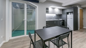 A compact kitchen with modern appliances, a dining area with a table and chairs, and a sliding glass door leading to a balcony. - GuestReady - Olivieri's House - 1 (Porto)
