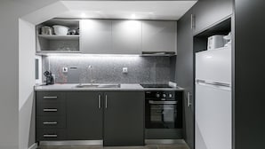 A compact kitchen with dark cabinetry, a granite countertop, a built-in oven, and a refrigerator. - GuestReady - Olivieri's House - 1 (Porto)