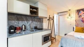 A compact kitchen with a marble countertop, a built-in oven, and a coffee maker.