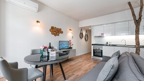 Een modern appartement met een eethoek, een bank, een keuken en een televisie.