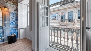 Een kamer met een grote glazen deur die uitkomt op een balkon met versierde metalen hekwerk.