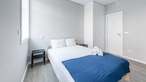 A modern hotel room with a large bed, a bedside table, a wardrobe, and a window. - GuestReady - Olivieri's House - 3 (Porto)