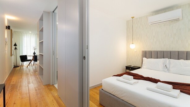 Una habitación de hotel moderna con cama, mesita de noche y un equipo de aire acondicionado.