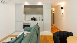 Un espacio habitable moderno y compacto con kitchenette, comedor y zona de estar.