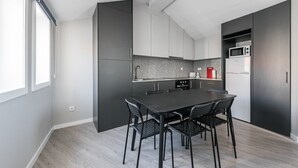 A modern kitchen with a dark countertop, white cabinets, and a black dining table with chairs.