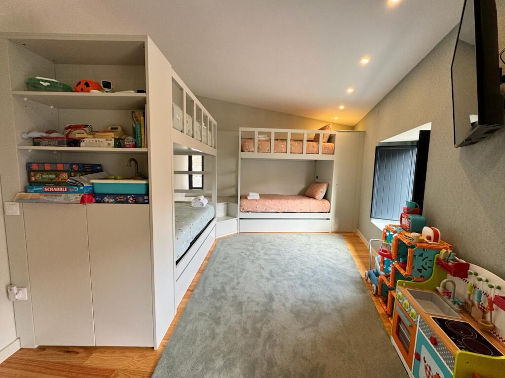 A compact room with a bunk bed, a small desk, and a toy kitchen set.