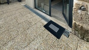 En modern byggnad med en fasad av sten, stora skjutdörrar av glas och ett metallgaller vid entrén.