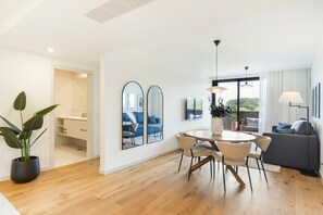Een moderne woonkamer met een eethoek, grote spiegels en een potplant.
