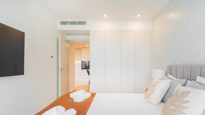 A hotel room with a bed, a TV, a wardrobe, and a bathroom visible through an open door. - GuestReady - Asaf's Magnolias Retreat (Vila Nova de Gaia)