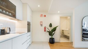A modern kitchen with white cabinets, a coffee machine, and a potted plant. - GuestReady - Asaf's Magnolias Retreat (Vila Nova de Gaia)