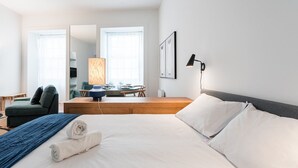 Moderni hotellihuone, jossa on suuri sänky, työpöytä, tuoli ja ruokapöytä.