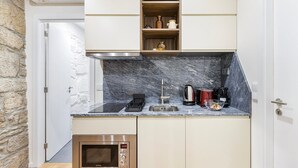 A compact kitchen with a built-in oven, a microwave, and a sink. - GuestReady - Caldeireiros Building (Porto)