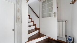 A staircase leading to a second floor, a white door with a frosted glass window, and a radiator on the wall. - Garden-inspired retreat (Celeiros)