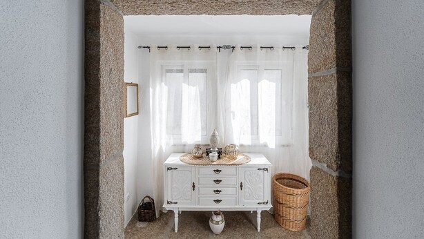 A white cabinet with drawers and a decorative top, placed in front of a window with white curtains. - Garden-inspired retreat (Celeiros)