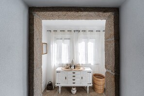 A white cabinet with drawers and a decorative top, placed in front of a window with white curtains. - Garden-inspired retreat (Celeiros)