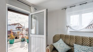 A room with a sliding glass door leading to a balcony with potted plants. - Garden-inspired retreat (Celeiros)